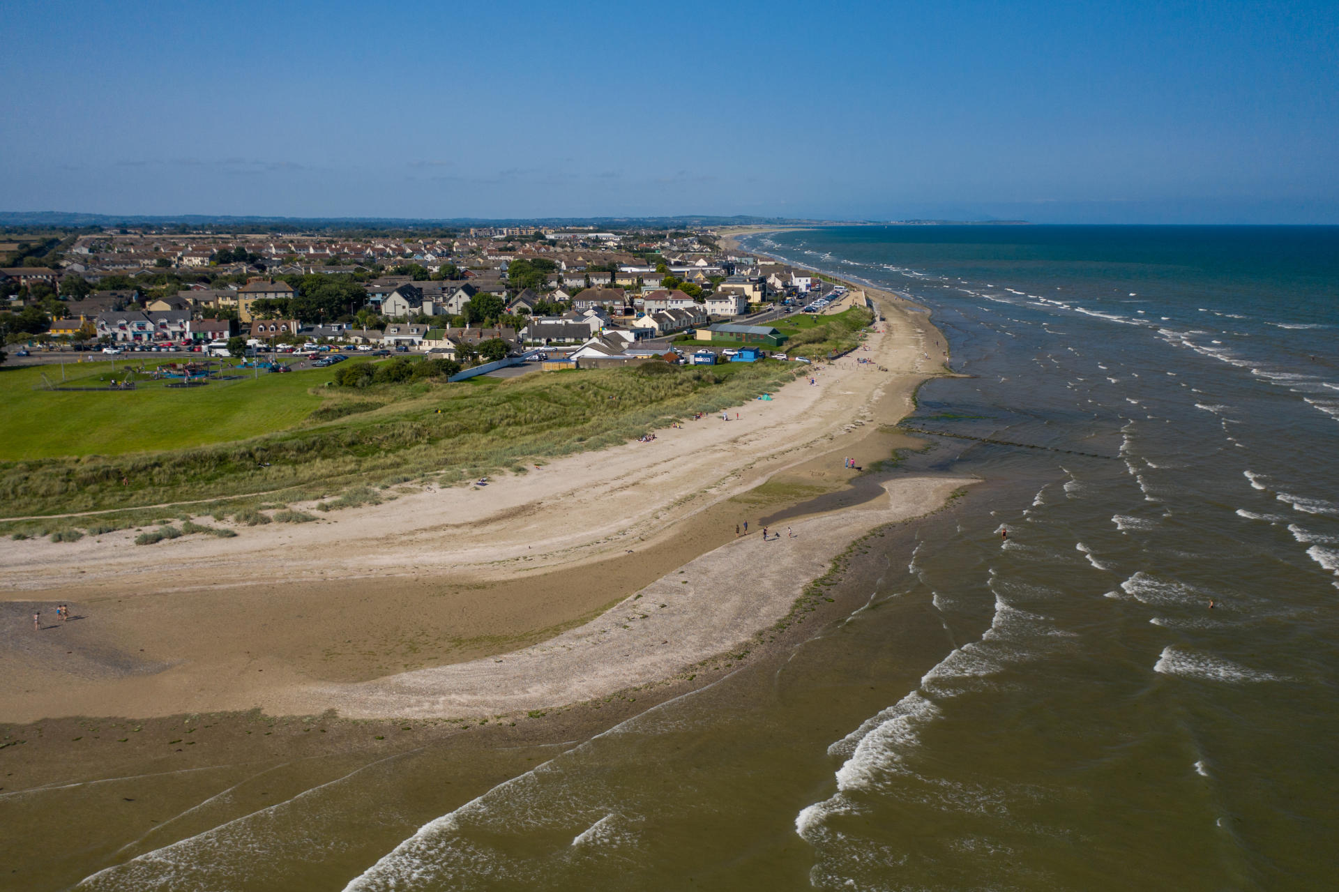 Aerial view of ocean waves hitting the coast near a town.