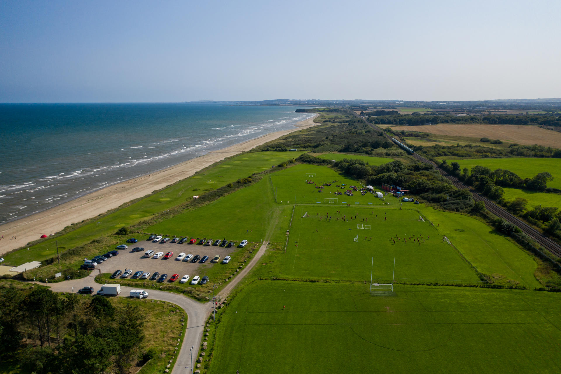 Aerial view of ocean, a beach, and green fields.